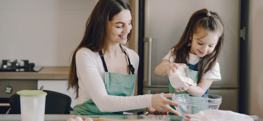 A joyful mother and daughter bonding while baking in the kitchen, smiling and enjoying the activity.